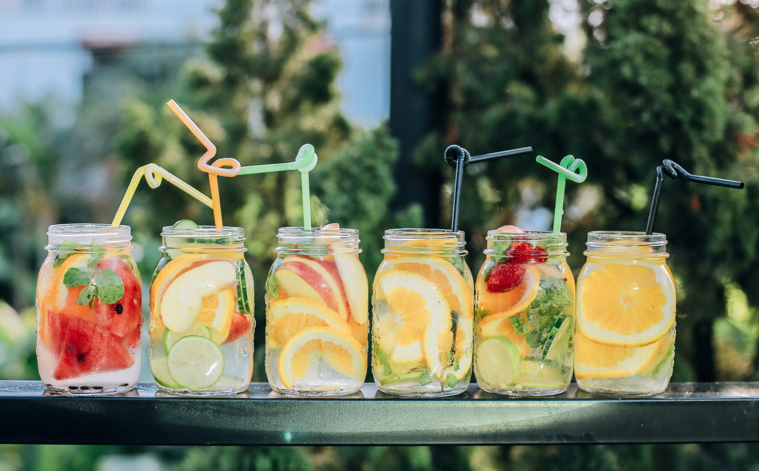 six clear glass mason jars filled with juice on black table